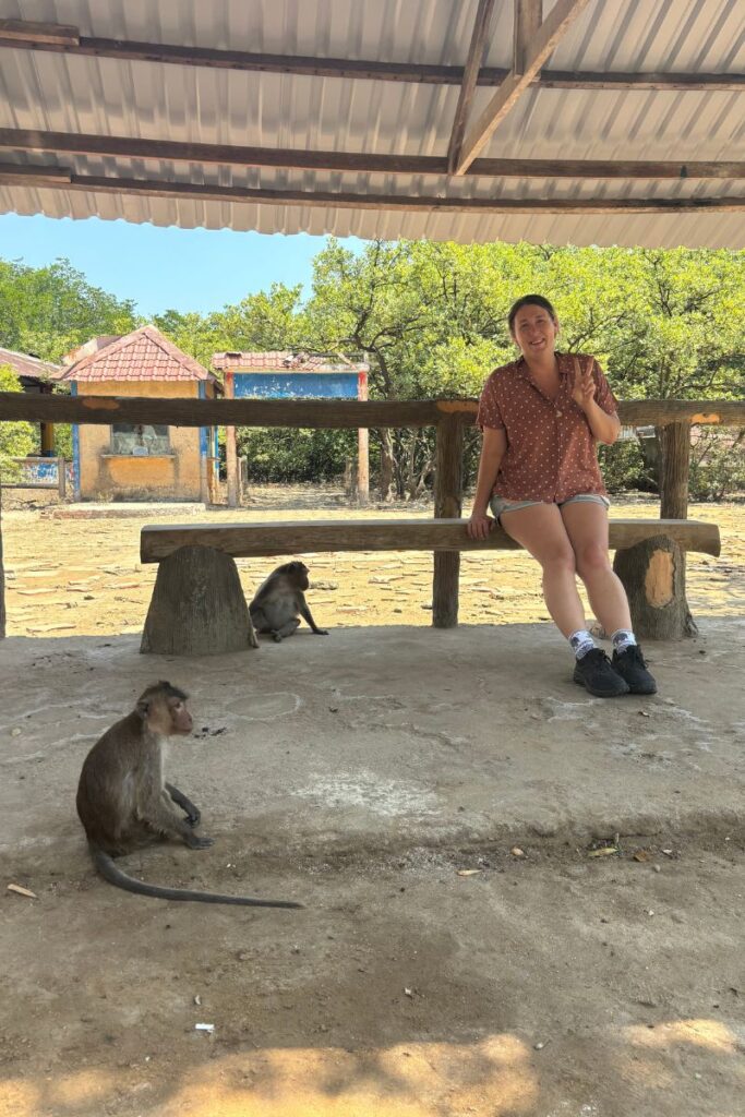 Sitting on a wooden bench while monkeys roam nearby at Monkey Island in Can Gio, a popular day trip from Ho Chi Minh City.