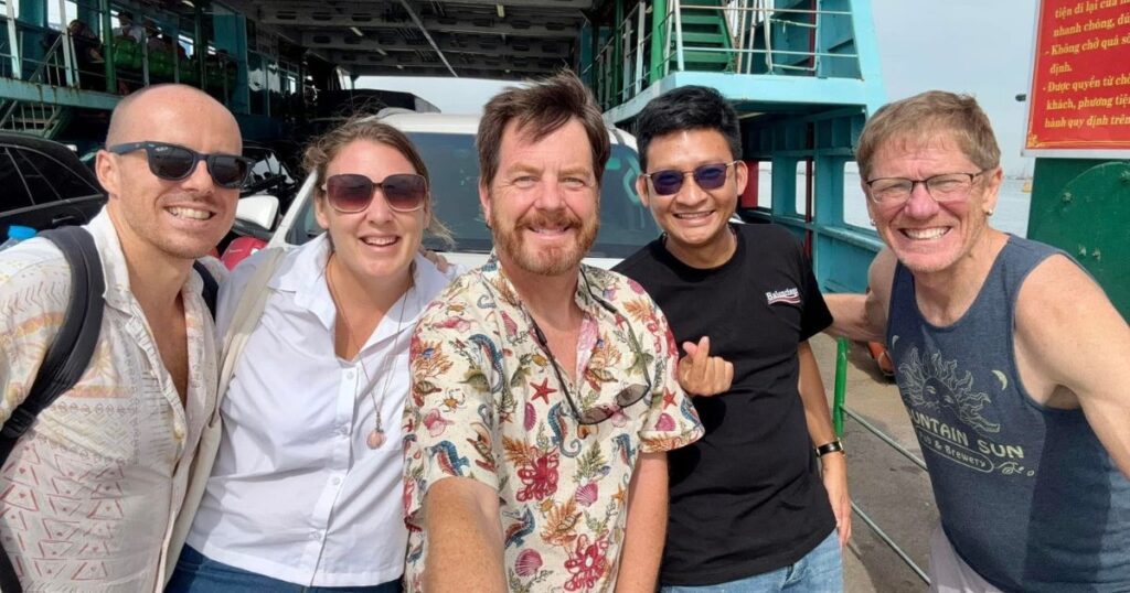 Group of us travelers smiling with their private driver at the ferry terminal before heading to Monkey Island HCMC.