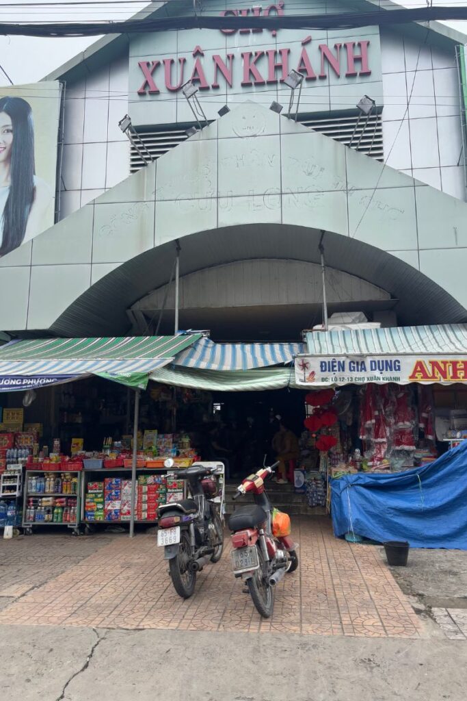 Two motorbikes parked outside a colorful local shop stacked with goods in a Vietnamese market — shopping here is one of the classic things to do in Can Tho.