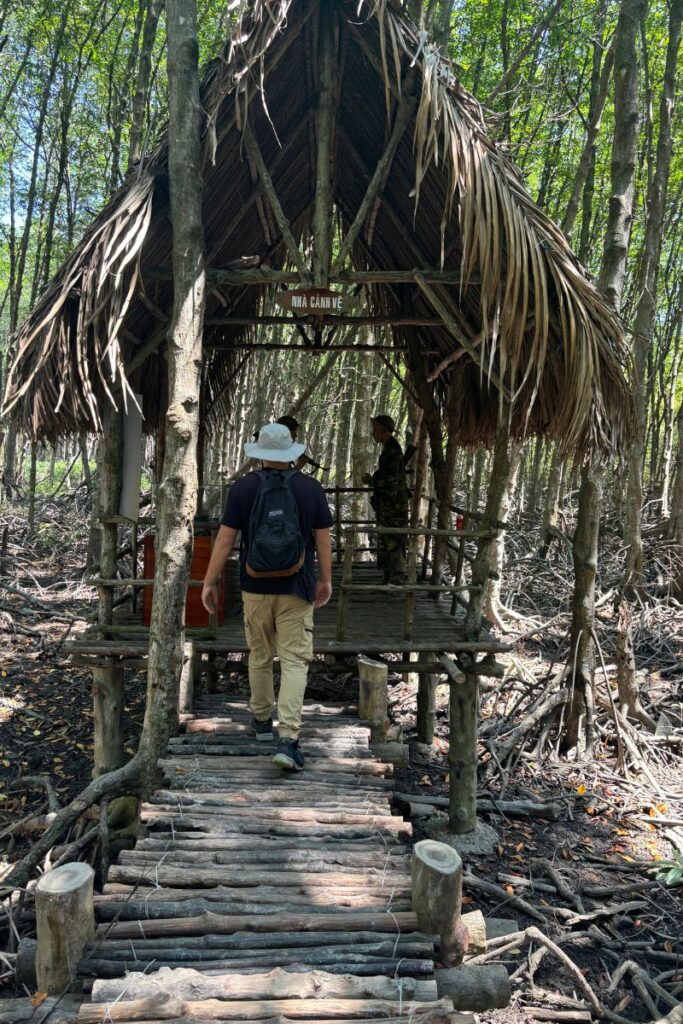 Visitor through the Rung Sac Guerrilla Base museum at Monkey Island in Can Gio, surrounded by dense mangrove forest.