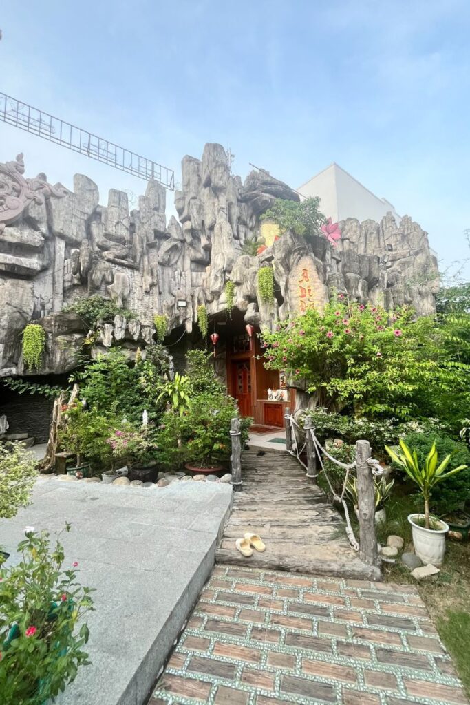 Lush entryway to a hidden Buddhist temple carved into a rocky façade, one of the more unique Can Tho attractions to explore.