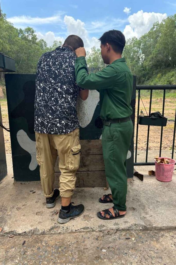Garret fires an AK-47 with the assistance of a park employee at Cu Chi Tunnels 