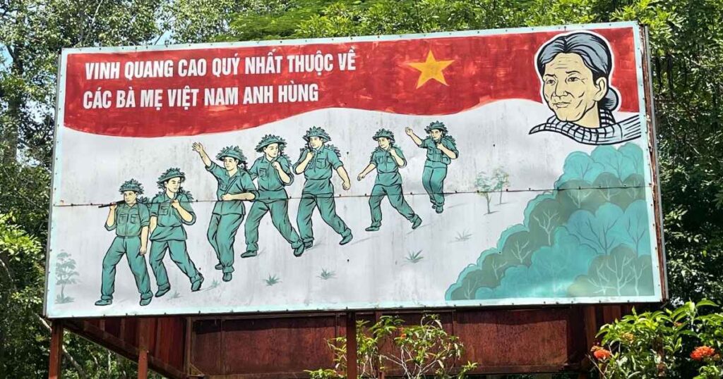 A sign that shows women marching and says "The highest glory belongs to the heroic Vietnamese mothers" in Vietnamese 
