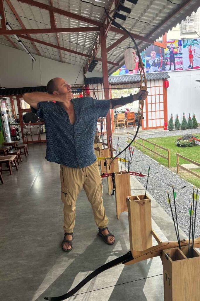 Aiming a bow at an indoor archery range in Da Nang, showcasing a unique and adventurous option for what to do in Da Nang beyond the usual tourist spots.