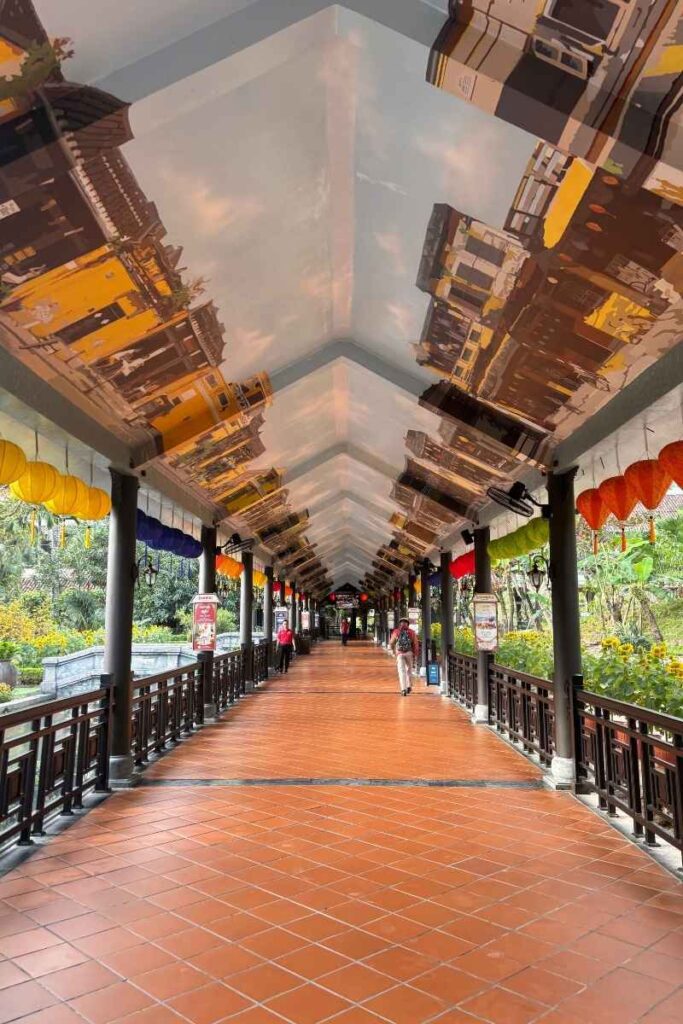 Covered walkway at Ba Na Hills decorated with colorful lanterns, leading toward the gondola boarding area near the ticket entrance.