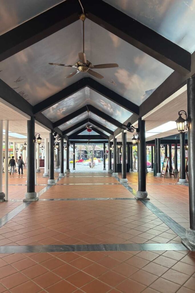 Covered walkway near the Ba Na Hills ticketing area, tiled floor, and directional signs visible in the distance.