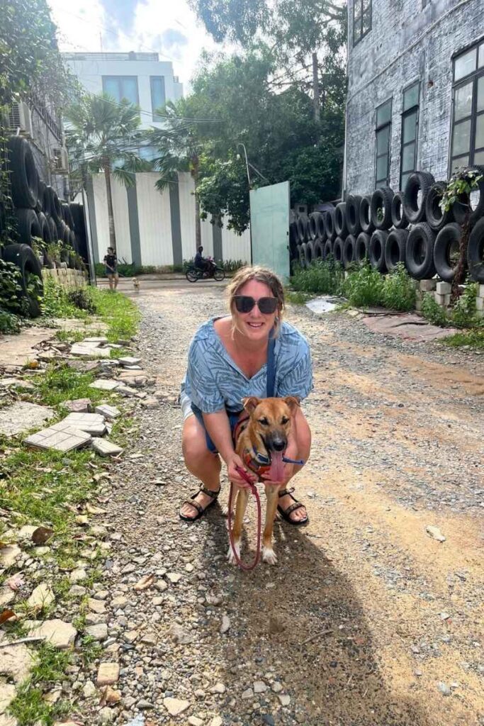 Megan crouching on a dirt path with a rescue dog at an animal shelter in Ho Chi Minh City, a meaningful experience among things to do in HCMC.