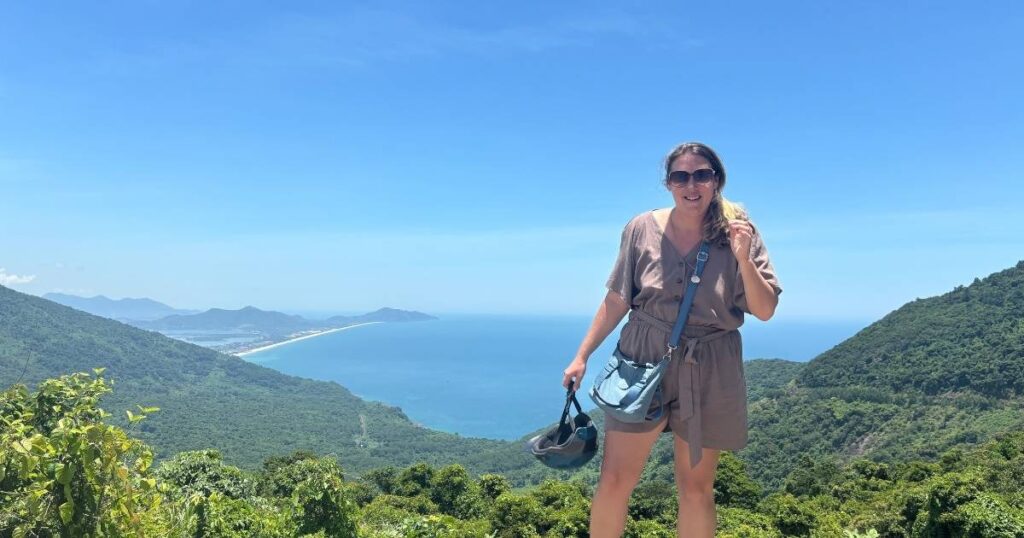 Posing at a viewpoint on Hai Van Pass with mountain greenery and ocean views.