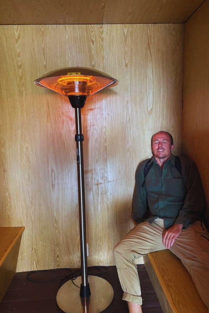 Man sitting and resting in a small wooden heating room inside the cathedral at Ba Na Hills French Village.