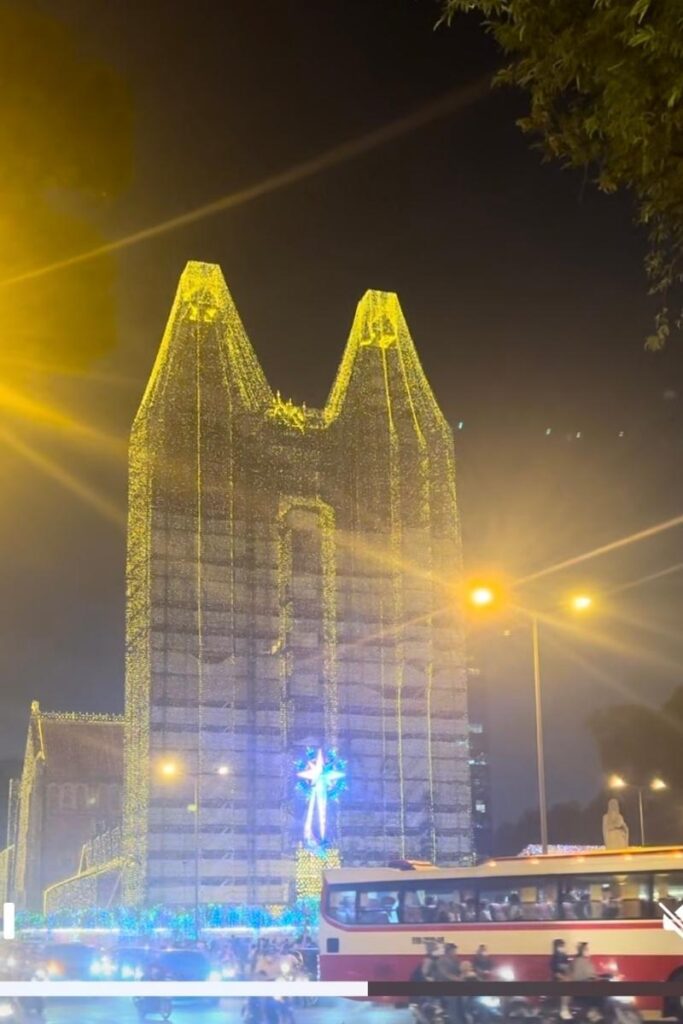 Saigon Notre-Dame Cathedral lit up with yellow Christmas lights and decorations at night in Ho Chi Minh City, a festive highlight.