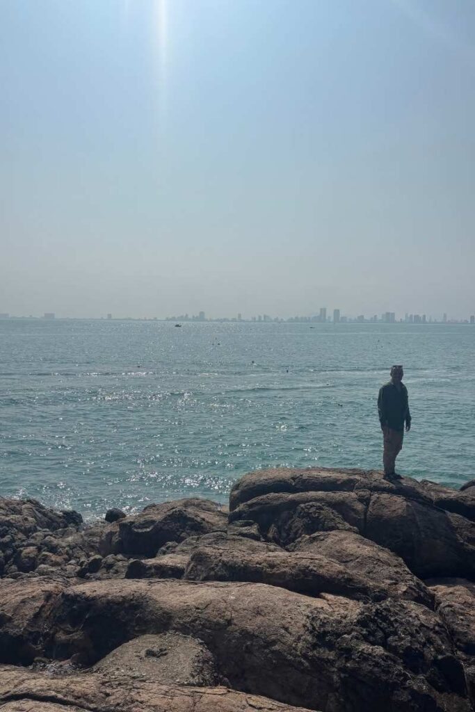 Silhouetted and standing on rocky cliffs overlooking the ocean at Secret Beach in Da Nang, a hidden gem perfect for quiet escapes and off-the-beaten-path Da Nang activities.