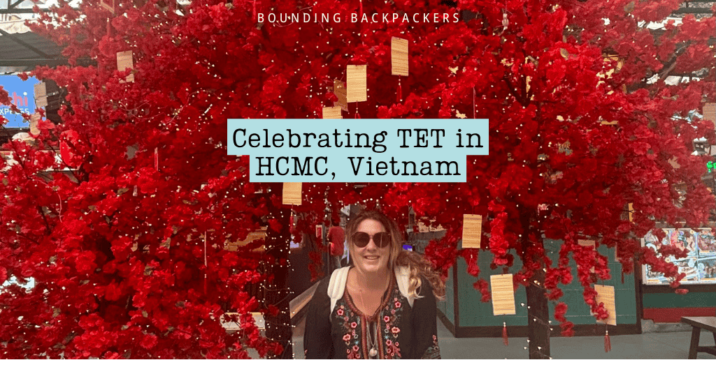 Celebrating Tet in Ho Chi Minh City with a vibrant red display featuring a decorative Tet tree covered in red envelopes, with a smiling woman seated underneath.