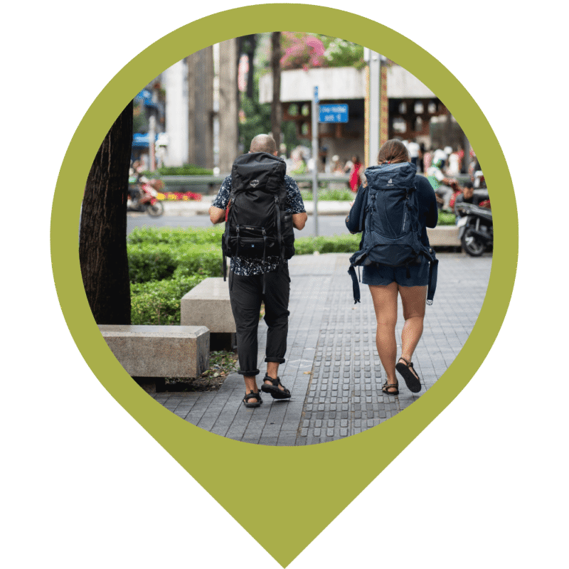 Hero Image of two people with backpacks walking down the street in Ho Chi Minh City, Vietnam