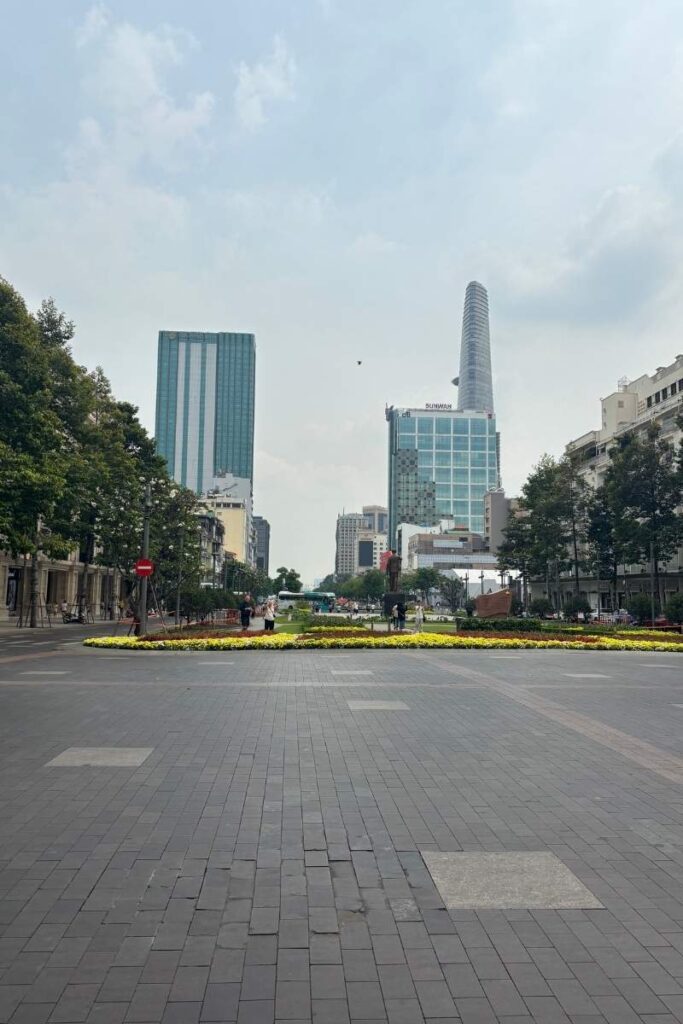 A nearly empty Nguyen Hue walking street in Ho Chi Minh City during Tet, with a view of Bitexco Tower in the background and colorful flower beds in the median.